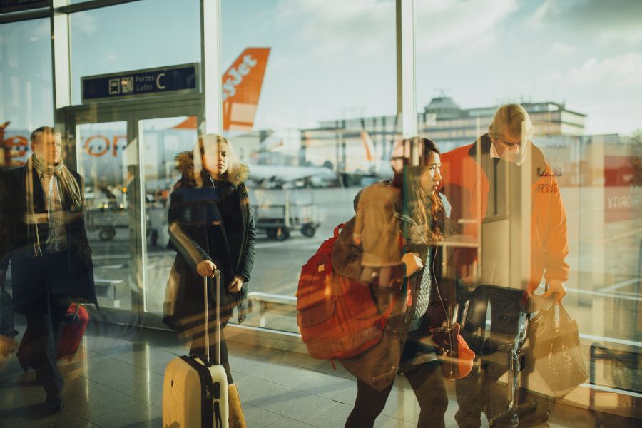 Dans un hall d'aéroport des passagers en manteaux poussent de grandes valises