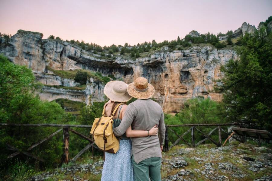 Un couple contemple une immense falaise rocheuse sculptée par la nature en s'enlaçant.